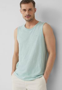 Helles blaues ärmelloses Shirt aus weichem Stoff, mit rundem Halsauschnitt und einem kleinen, dezenten Logo auf der Brust. Lockere Passform.
