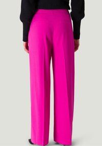 Pantalones de pierna ancha fucsias, confeccionados con una tela suave, que cuentan con dos bolsillos traseros y un corte entallado, combinados con una blusa de punto negra.