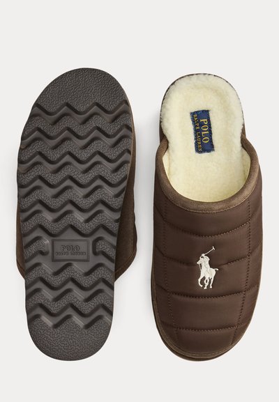Bruine doorgestikte pantoffels met wit Polo Ralph Lauren-logo, crèmekleurige fleecevoering en zwarte rubberen zool met golfpatroon en Polo Ralph Lauren-tekst.