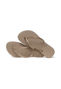 Beige flip-flop sandal med teksturerte såler og tynne metalliske stropper, med en svak kurve og subtil merking på fotputen.