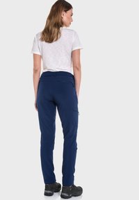 Marine Cargo-Hosen mit mehreren Taschen, aus weichem Stoff gefertigt. Sie verfügen über eine taillierte Passform und gerade Beine, kombiniert mit robusten schwarzen Schuhen.