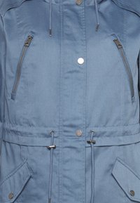 Niebieska kurtka z kapturem, z zamykanymi kieszeniami na piersi, regulowanymi sznurkami, zatrzaskami oraz teksturowanym materiałem z kieszeniami bocznymi.