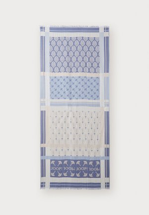 Textile scarf featuring alternating patterns in blue and cream, with leaf and floral motifs. Edges are fringed. Logo displayed at the bottom.