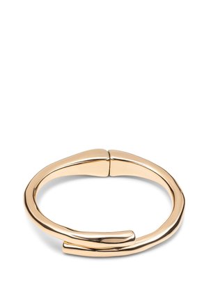 Pulsera de metal tono dorado con un diseño suave y curvado. Presenta un espacio en el cierre, destacando su forma minimalista y acabado pulido.