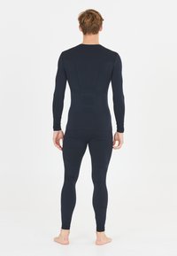 Czarny, dopasowany strój sportowy składa się z bluzki z długim rękawem oraz legginsów o pełnej długości, z teksturowanym wykończeniem na plecach.