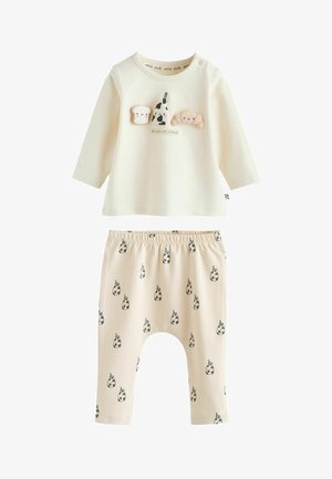 Bluză cu mâneci lungi, culoare crem, cu aplicații tematice alimentare; pantaloni cu talie elastică, imprimeu cu vaci. Țesătură moale din bumbac, croială lejeră pentru confort.