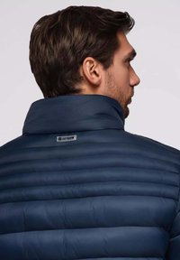 Dunkelblaues Puffer-Jackett mit hohem Kragen und horizontalen Nähten, ausgestattet mit einem Logo-Tag auf der Rückseite und glattem, wasserabweisendem Stoff.
