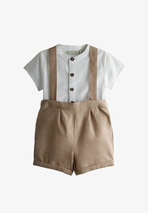 Camisa blanca de mangas cortas con tres botones marrones combinada con pantalones cortos beige de tiro alto con tirantes incorporados.