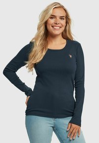 Langermet ribbestrikket topp i mørkeblått stoff; har rund hals og liten brodert design på brystet; tettsittende silhuett.