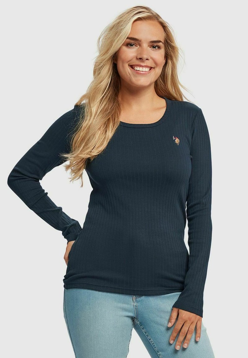 Langermet ribbestrikket topp i mørkeblått stoff; har rund hals og liten brodert design på brystet; tettsittende silhuett.