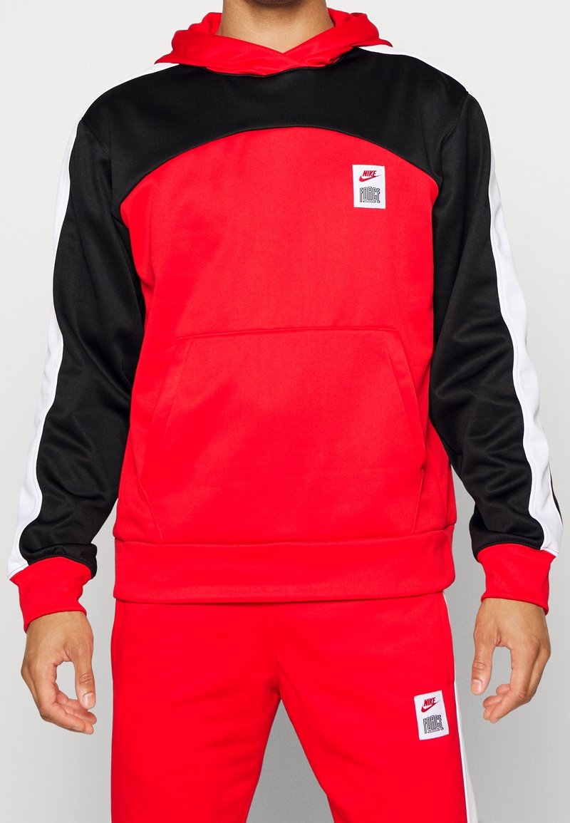 Sweat à capuche rouge et noir avec des bandes blanches sur les côtés. Comprend une poche kangourou et une petite étiquette Nike sur le devant. Texture lisse.