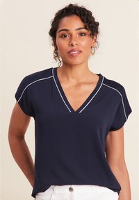 Marineblaues kurzärmliges Oberteil mit V-Ausschnitt und weißem Kontraststich. Leichter Stoff mit lockerer Passform und glatter Textur.