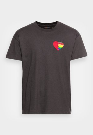 T-shirt en coton noir à col rond, orné d'un motif de cœur brodé en rouge et aux couleurs de l'arc-en-ciel, situé sur la partie gauche de la poitrine.