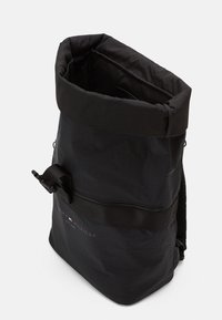 Sac à dos noir à rabat fabriqué en tissu durable, avec une finition texturée, une sangle réglable et une poche zippée avec un détail de logo.
