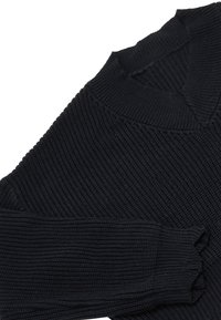 Schwarzer, gerippter Strickpullover mit hohem Kragen und Rüschensaum. Das Material wirkt strukturiert und hat eine weiche Oberfläche.
