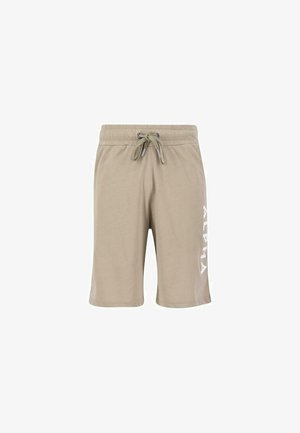 Pantalones cortos de algodón beige con cinturilla elástica, cordón ajustable y gráfico blanco "ALPHA" en el lado izquierdo. Textura suave, diseño informal.