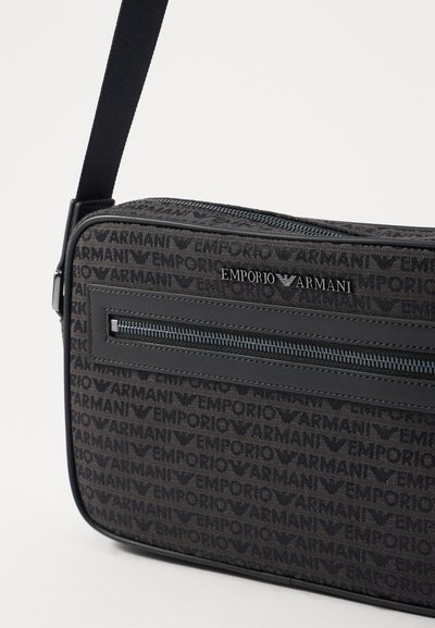 Black fabric shoulder bag featuring an all-over Emporio Armani logo pattern, zippered compartments, and a durable adjustable strap.