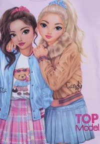 Due ragazze illustrate in abiti pastello. Una indossa una giacca bomber azzurro chiaro sopra una maglietta con un orso. L'altra ha una giacca con colletto in pelliccia color sabbia.