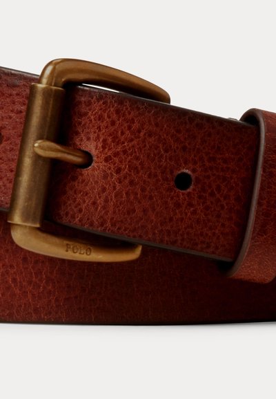 Pruun tekstuuriga nahast rihm messingist pandlaga, millele on graveeritud "POLO", näidates ühte auku ning nahast rihmaringi.