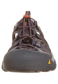 Męskie buty outdoorowe z szarym tekstylnym wierzchem, pomarańczowymi akcentami i szarą gumową podeszwą. Charakteryzują się konstrukcją wsuwana z elastycznymi sznurowadłami i osłoną palców.