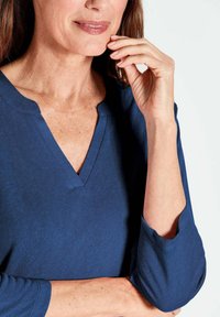 Marineblaue V-Ausschnitt-Oberteil mit langen Ärmeln, aus weichem Baumwollstoff, mit lockerem Schnitt und subtilen Nähdetails.