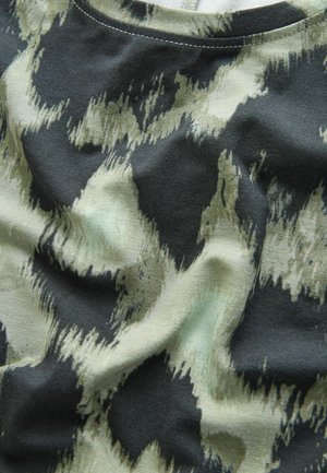 Suure plaaniga kortsus kangas, millel on abstraktne must ja beež muster ning nähtavad õmblused ääres.