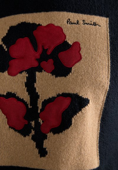 Πλεκτό πουλόβερ με μεγάλο κόκκινο λουλουδάτο σχέδιο σε μπεζ φόντο με μαύρες λεπτομέρειες. Υπογραφή "Paul Smith" στην επάνω γωνία.