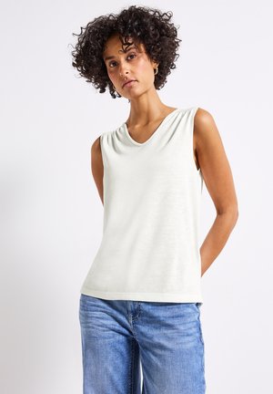 Lichtgrijze mouwloze top met een V-hals, zachte textuur, subtiele schouderplooien, gecombineerd met blauwe denim jeans.