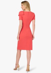 Koralowa sukienka z krótkimi rękawami i kokardkami na ramionach. Dopasowany krój z zamkiem na plecach. Gładka, elastyczna tkanina.