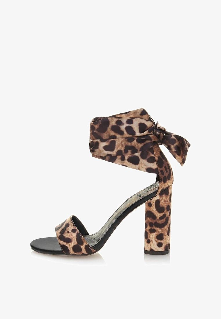 Sandale à talons hauts en imprimé léopard avec une large sangle autour de la cheville, un détail de nœud et une semelle noire unie. Tissu texturé et design de talon block.