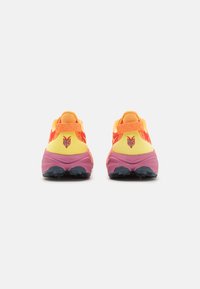 Chaussures de sport avec une tige en mesh jaune, des accents orange et une semelle en caoutchouc rose. Présente un logo à l'arrière et une surface texturée.
