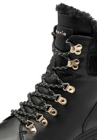 Schwarze Lederschuh für Wanderungen mit einem Kragen aus Kunstfell, goldenen Ösen und schwarz-weißen gesprenkelten Schnürsenkeln. Robuste Konstruktion, strukturierte Oberfläche.