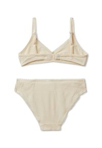 Sujetador beige y bragas a juego hechas de tela texturizada, con tirantes ajustables, bordes con forma de ondas y un cierre de gancho en la parte posterior.