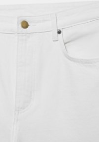 Gros plan de la ceinture d'un jean en denim blanc avec un bouton en laiton, une passants de ceinture et des détails de couture sur la poche avant.