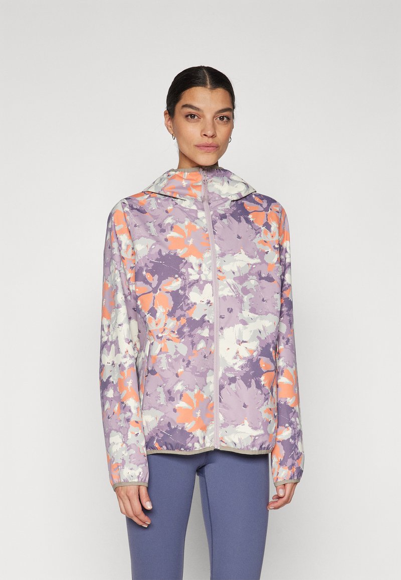 Chaqueta ligera con cierre de cremallera en la parte delantera, con un patrón floral en tonos morados y acentos en naranja y blanco. Cuenta con capucha y mangas largas. Textura suave.