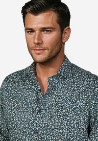 Bloemenoverhemd met een donkerblauwe achtergrond, met kleine witte en gele bloemen, knoopsluiting en een gestructureerde stof.