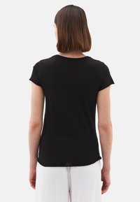 T-shirt nera a maniche corte con scollatura rotonda e orlo leggermente curvato. Realizzata in tessuto morbido, ha una vestibilità rilassata.