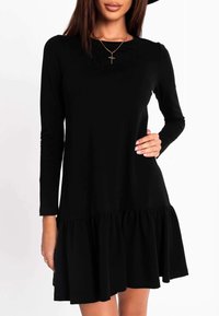 Schwarzes, langärmliges Kleid mit einem ausgestellten, gestuften Saum. Hergestellt aus weichem Stoff, mit einem runden Ausschnitt und dezenten Raffungen an der Taille.