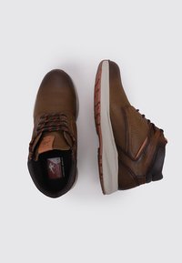 Chaussures à cheville en cuir brun avec des accents sombres contrastants. Présentent une tige texturée, une semelle en caoutchouc et des lacets contrastants en orange et noir.