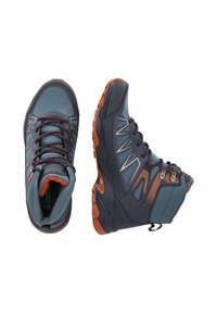 Vandringskängor i mörkblått och grått med orange accenter. Har en texturerad syntetisk ovandel, gummisula och ett säkert snörningssystem.