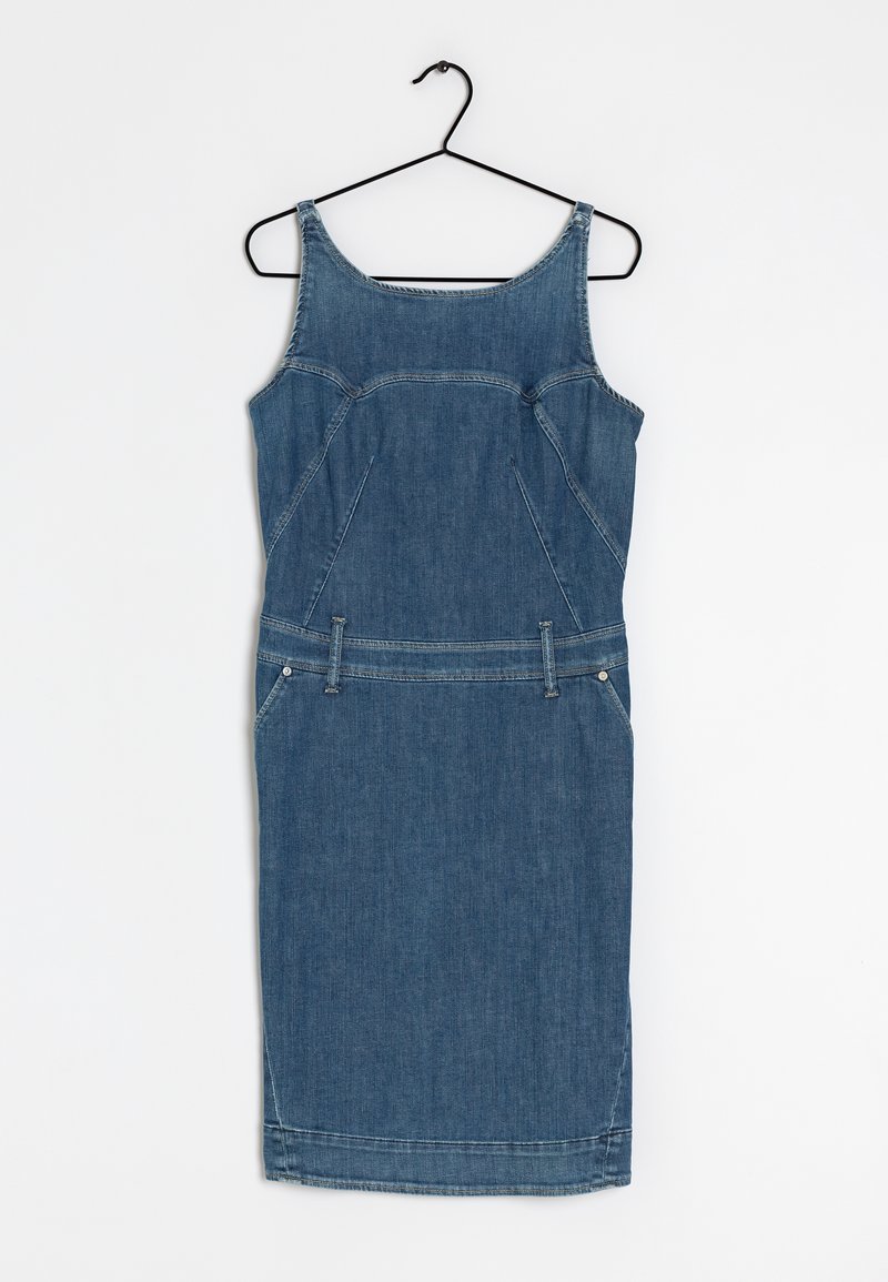 Robe en denim bleu sans manches, longueur genou, avec passants de ceinture, suspendue sur un cintre en fil noir devant un fond blanc uni.
