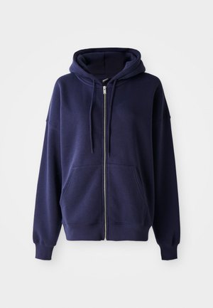 Felpa con zip blu navy realizzata in tessuto morbido, dotata di un ampio cappuccio, tasche frontali e polsini e fondo a coste per una vestibilità rilassata.