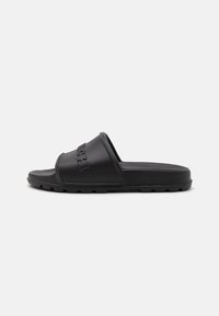 Black slide sandal made of rubber, featuring a textured strap with embossed lettering and a flat sole with small grooves for traction.