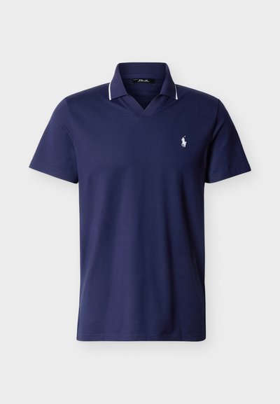Μπλε ναυτικού κοντομάνικο πόλο με λευκή επένδυση στον γιακά και μικρό λευκό κεντητό λογότυπο στο αριστερό μέρος του στήθους.