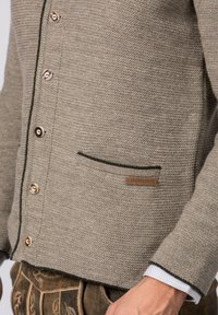 Grauer Strickcardigan mit strukturiertem Finish, kontrastierendem dunkelgrünem Besatz, sechs bronzefarbenen Knöpfen und einem kleinen Lederlabel an der Tasche.