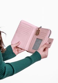Light pink zip wallet featuring multiple card slots, a clear ID window, and a decorative charm. Smooth texture with stitched accents.