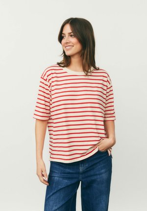 Red and white striped short-sleeve shirt, soft fabric, relaxed fit, rounded neckline, paired with dark denim jeans, casual design.