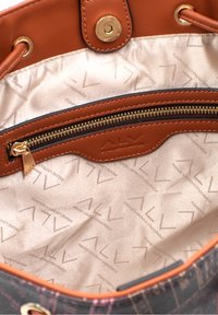 Interno di una borsa in pelle marrone con una fodera beige, dotata di una tasca con zip e un motivo in rilievo del logo. Accenti in metallo dorato.