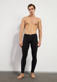 Black fitted leggings in a stretchy, smooth material. Features a comfortable waistband and a slim silhouette. No patterns or accents.
