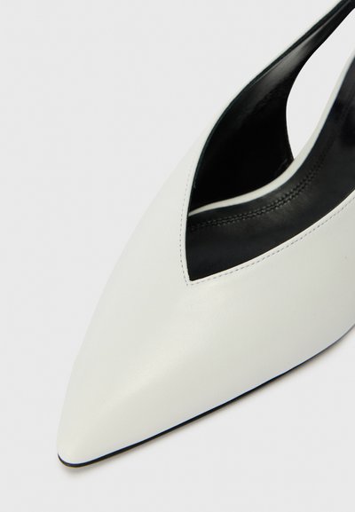Sapato slingback em couro branco com bico pontudo, recorte em V profundo e interior preto. Textura suave com detalhes de costura mínimos.